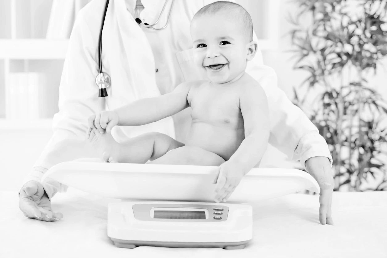 Smiling infant sitting on a baby scale