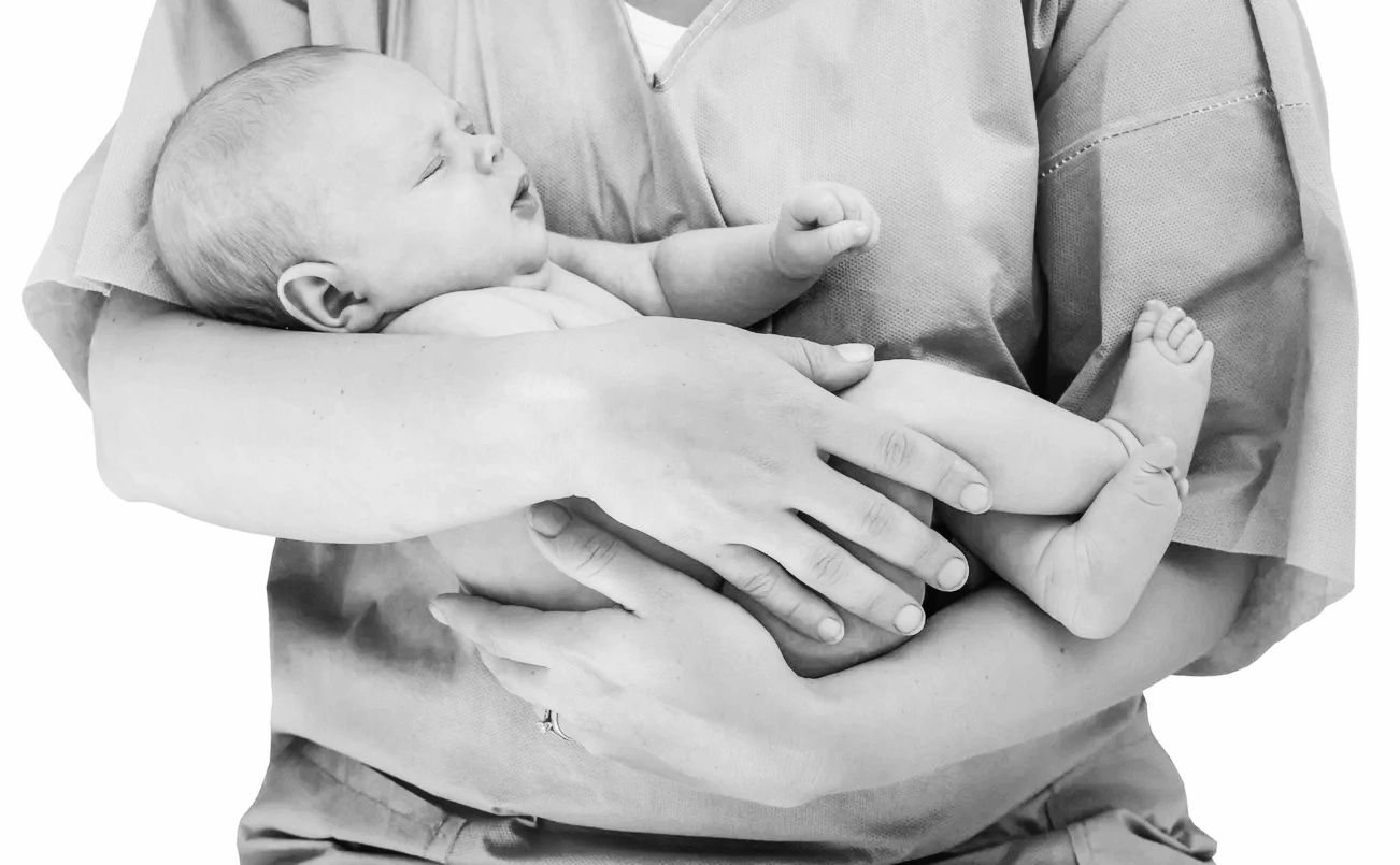 Newborn held in a caregiver’s arms