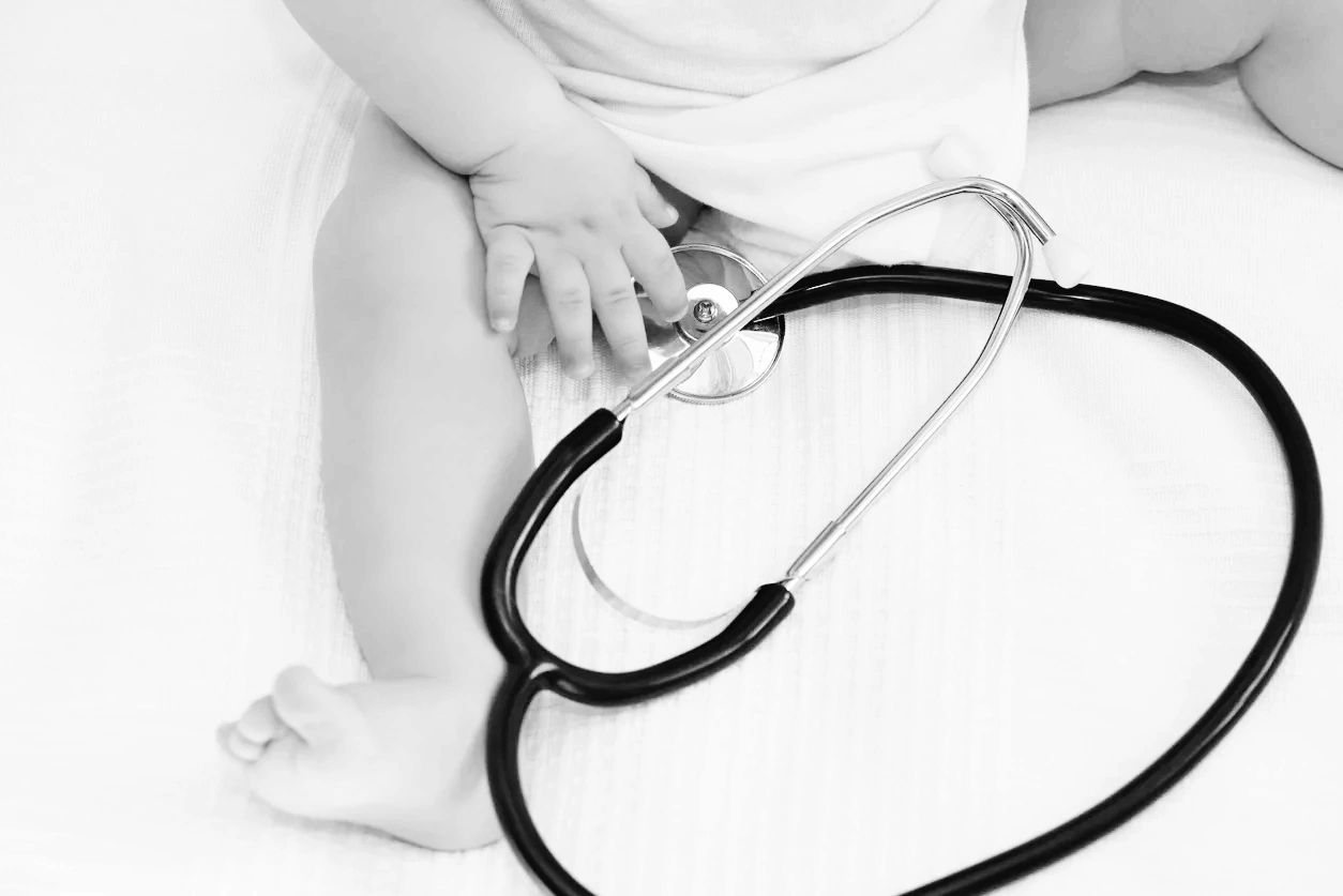 Infant lying on a blanket next to a stethoscope